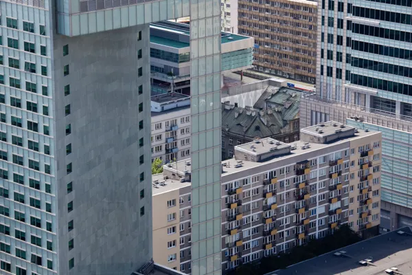 Warszawska zabudowa mieszkaniowa — kontrast nowoczesnych apartamentowców ze szklanymi elewacjami i starszych bloków mieszkalnych, ilustrujący transformację rynku deweloperskiego w stolicy