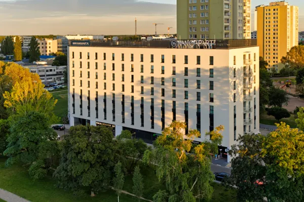 Budynek Nano Apart przy ul. Grochowskiej 67 w Warszawie – nowoczesny obiekt w otoczeniu zieleni, widok z lotu ptaka o zachodzie słońca